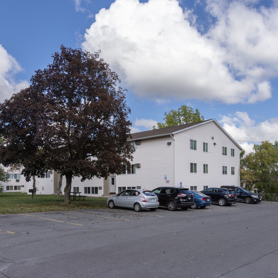 Three-story building, red-leaf tree and parking lot at Brook Manor Apartments, Syracuse NY