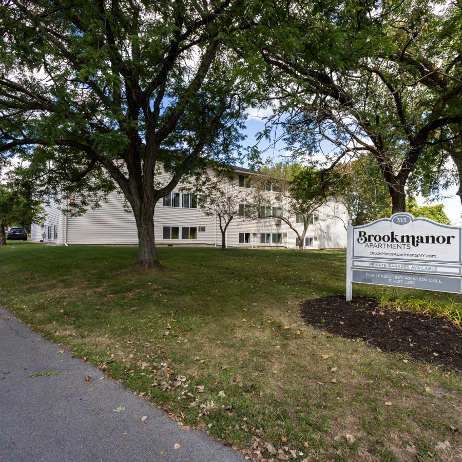 Entrance sign beside the walkway and lawn at Brook Manor Apartments, Syracuse NY