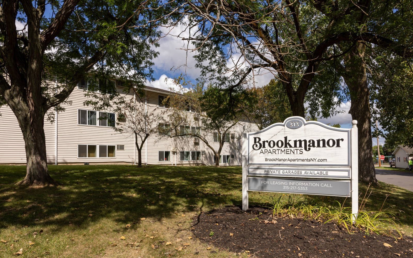 Brook Manor entrance sign on the lawn under shade trees at Brook Manor Apartments, Syracuse NY