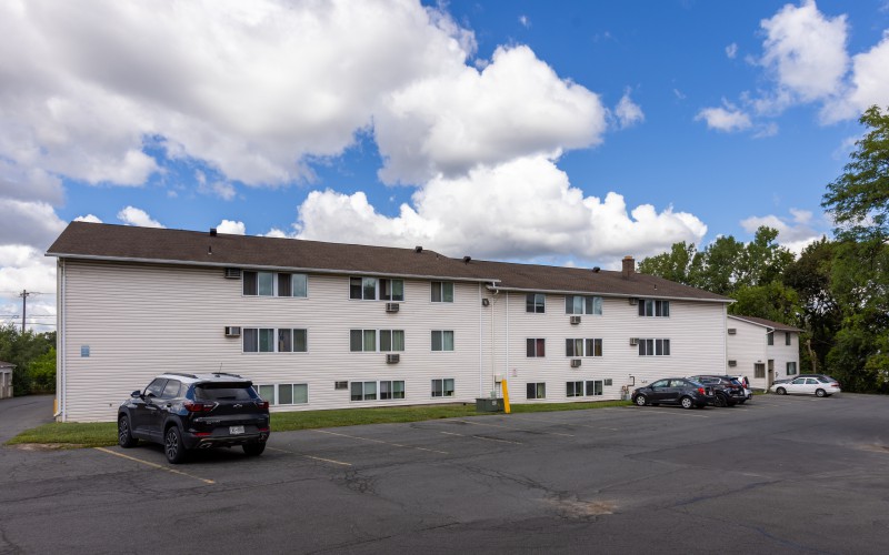 Long three-story apartment building and parking at Brook Manor Apartments, Syracuse NY