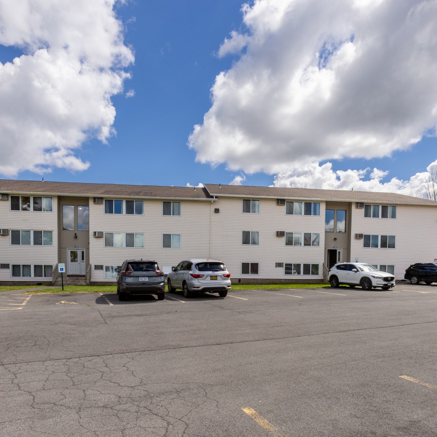 Three-story building across a wide parking lot at Brook Manor Apartments, Syracuse NY