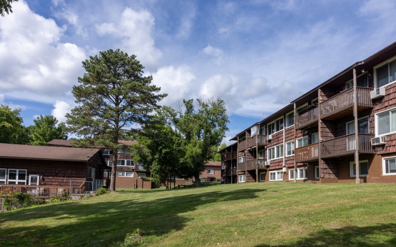 Sunny lawn and three-story apartment buildings at Carriage House Apartments, Syracuse NY